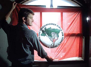 Gilmar Mauro coloca bandeira do MST em janela na sede do movimento, em São Paulo (Foto: Folha Imagem)