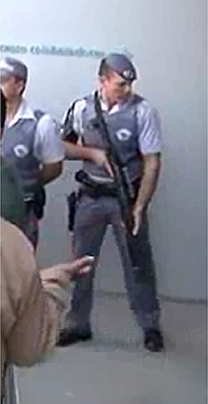 Policial com arma de grande porte intimida trabalhadores em greve por direitos na Medley/Sanofi-Aventis. Ironicamente, atrás dele, lê-se na parede: "Entrada de colaboradores",